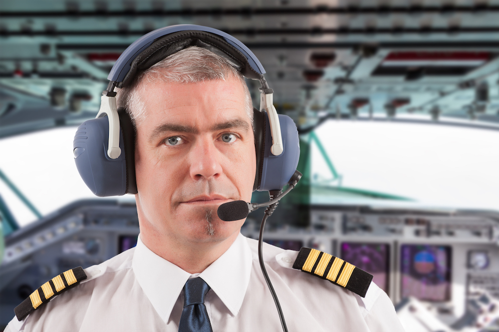Airline,Pilot,Wearing,Uniform,With,Epaulettes,And,Headset,,On,Board